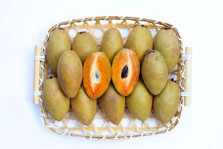 Fresh sapodilla fruit in bamboo basket on white background
