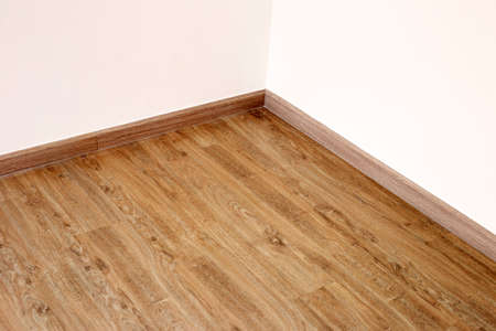 Laminate wood floor with blank white wallの写真素材