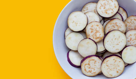 Fresh eggplant in bowl on yellow background.の写真素材