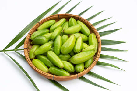 Bilimbi fruit in bamboo basket on white background.