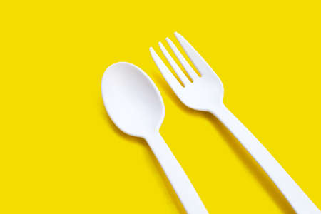 Plastic fork and spoon on yellow background.