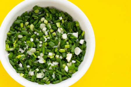 chopped spring onions on yellow background
