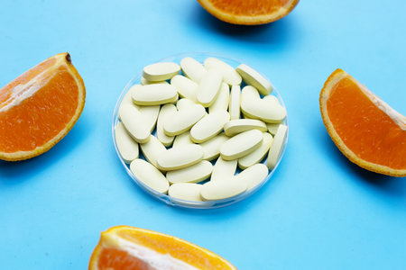 Vitamin c pills with orange fruit on blue background.の写真素材