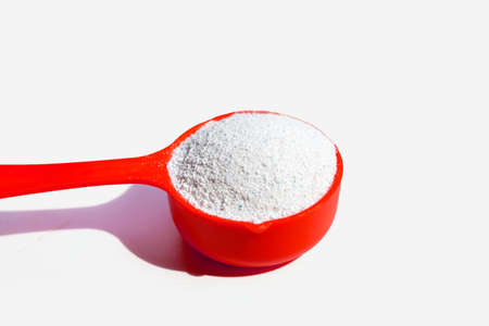 Detergent powder with measuring spoon for clothes washing. Laundry concept.