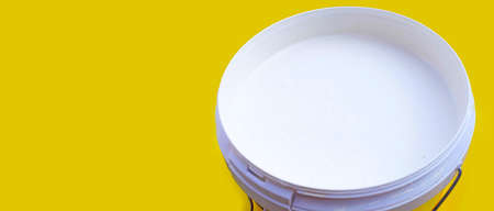 White paint in plastic bucket on yellow background.の写真素材