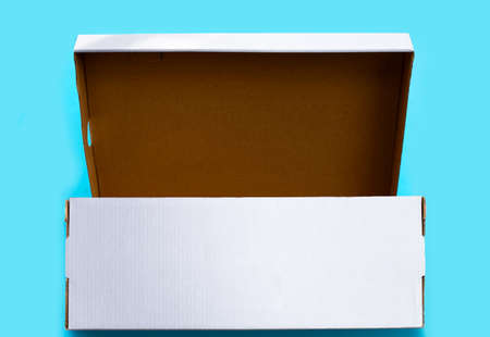 Open empty cardboard box on blue background.
