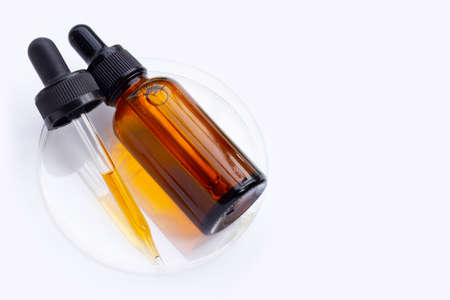 Essential oil bottle in petri dishes on white background.
