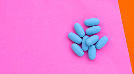 PrEP ( Pre-Exposure Prophylaxis) blue pills used to prevent HIV Blue pills in plastic bottle caps on pink paper surfaceの写真素材