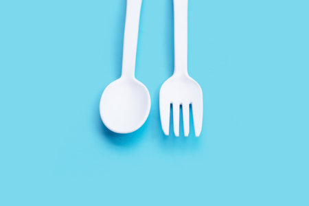 Plastic fork and spoon on blue background.の写真素材