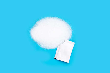 Granulated sugar with sugar sachet on blue background.の写真素材