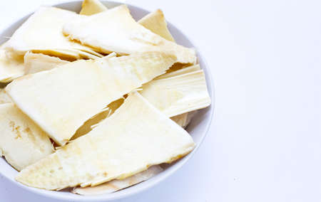 Sliced raw bamboo shoots in white bowl on white background.の写真素材