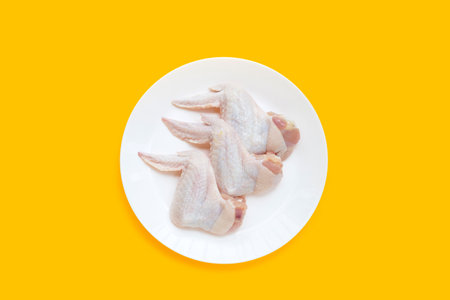 Fresh raw chicken wings in white bowl on yellow background.の写真素材