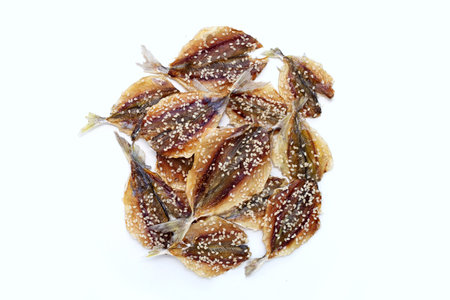 Dried fish with sesame seeds on white background.