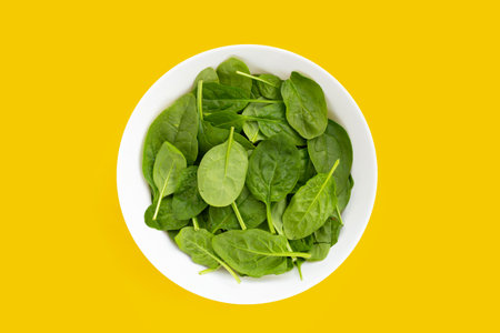 Spinach leaves on yellow background.