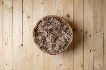 Basket covered with feathers on wood floor.の写真素材