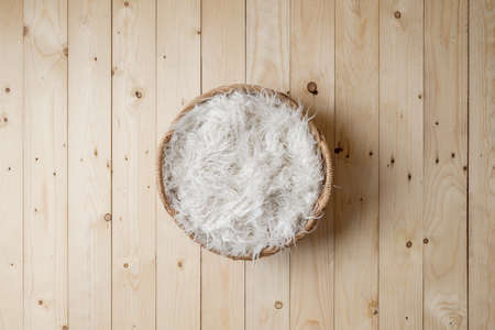 Basket covered with feathers on wood floor.の写真素材