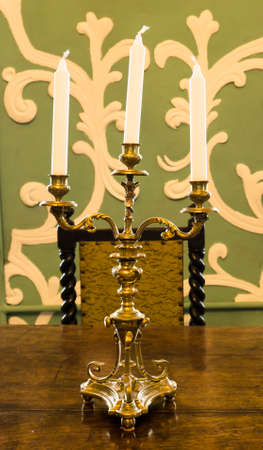 Gold candlestick with candles on the tableの写真素材