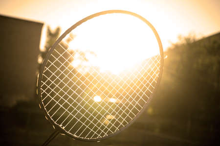 Tennis badminton racket under rays of sun glare bloom filtered background