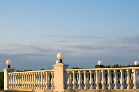 Decorative fence of columns on promenade on background of blue sky and clouds