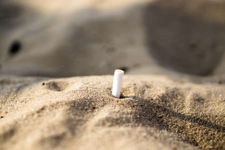 Smoked cigarette in sand hill macro backgroundの写真素材