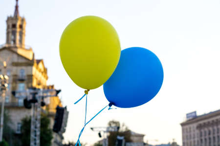 Flying balloons with colors of flag of Ukraine in city centerの写真素材