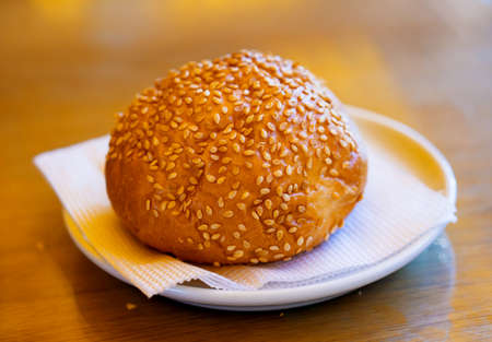 Golden fresh bun with sesame seeds on white plate with napkinの写真素材