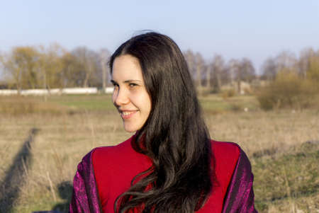 Portrait of young brunette girl in red jacket outdoorの写真素材