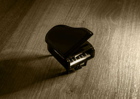 Miniature model of black grand piano with shadow on wooden table filteredの写真素材