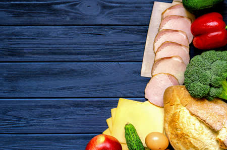 Set of products for cooking - apple, bell pepper, cucumber, fresh bread, eggs, sliced ham, broccoli, cheese, avocado and cleaver on sea blue vintage wooden work surfaceの写真素材