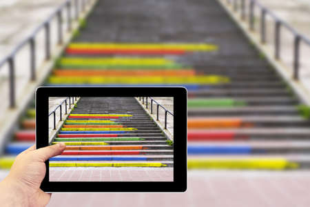 Tablet photography concept. Taking pictures on a tablet. Stairway in the form of pencils of rainbow colorsの写真素材