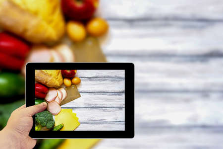 Tablet photography concept. Taking pictures on a tablet. Set of products for cooking on white vintage wooden work surfaceの写真素材