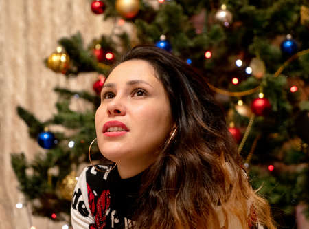 Young brunette girl in red dress celebrating new year. Christmass concept near Christmass tree with...