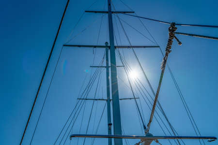 Mast of the yacht against the blue sky with sun glare. Summer recreation concept. High detailed photoの写真素材