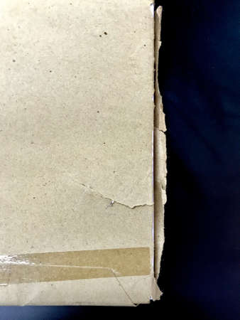 The rim of paper which is wrapped by a brown paper bag and plastic tape is put on the black tableの写真素材