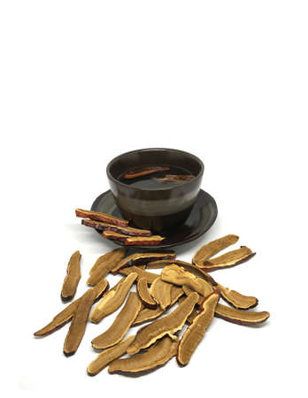 Dried sliced Lingzhi mushroom or Reishi mushroom are putting with the black cup of tea on the clean...