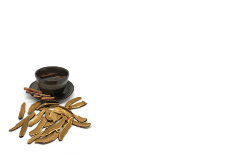 Dried sliced Lingzhi mushroom or Reishi mushroom are putting with the black cup of tea on the clean...