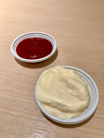 Ketchup and mayonnaise on a white plate on a wooden table