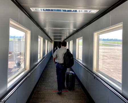 A man with a suitcase on the background of an airport window.