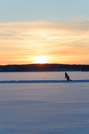 Ice skating in Scandinavia winter sunset on frozen lakeの写真素材