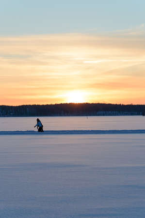 Ice skating in Scandinavia winter sunset on frozen lakeの写真素材