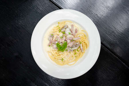spaghetti on white plate on black wooden background, spaghetti menu concept. Top view.の写真素材