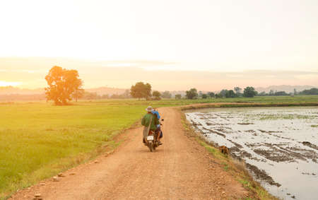 Farmers drive their motorcycles to the fields on beautiful nature background. rural dirt road,...