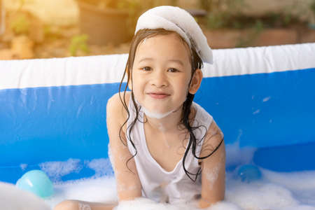 Beautiful Asian girl playing in an inflatable pool. Playing in the water at home during the summer....