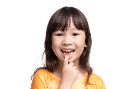 Cute Asian girl smiling showing her missing teeth in her mouth.Tooth loss by age concept,...