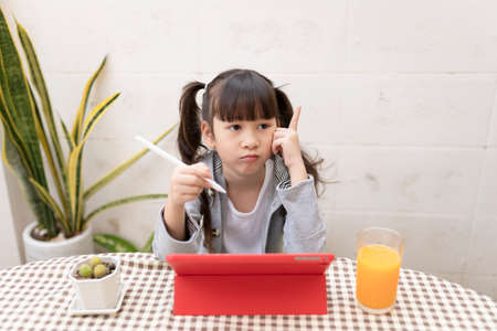 Asian schoolgirls study online with digital tablet at home. Child using gadgets to study. Education...