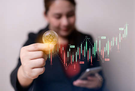 Business woman in hand bitcoin coins and smartphone with crypto trading chart. cryptocurrency...