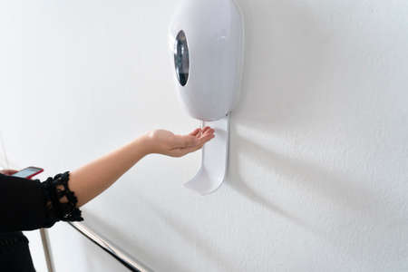 woman's hand using alcohol gel with automatic machine in the hospital for cleaning hands. Economical...