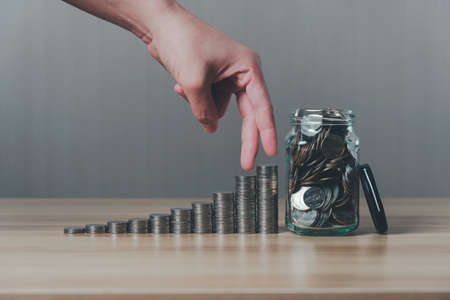 business and finance growth concept. Fingers walking up on coins stack and row of coin. collecting money, financial planning, save money for the future.の写真素材