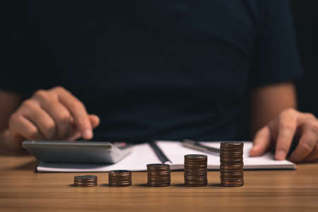 pile of coins or money growth on wooden table and business people investment concept in financial business. saving money. balance, investment, business growth and financial development.の写真素材