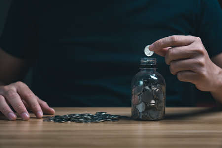businessman kept the money in the piggy bank on the table. financial stability management concept. Savings and pensions, collecting money, financial planningの写真素材